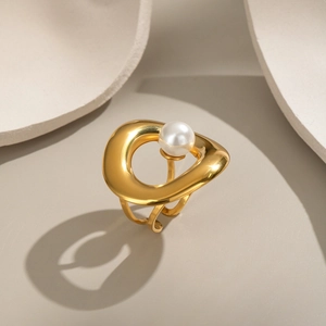 Artistic gold-plated stainless steel ring with elegant white pearl on geometric background