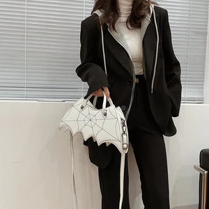 Detail of white bat-shaped PU leather handbag with spider web stitching worn by a model