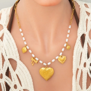 Detailed view of irregular white pearls with golden heart and sun pendants on a necklace