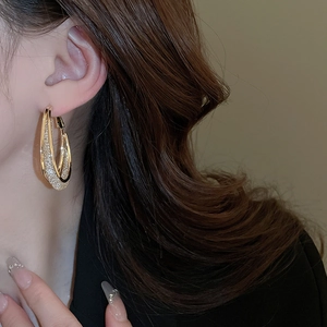 Close-up of dual-layer gold hoop earrings with sparkling rhinestones on female model