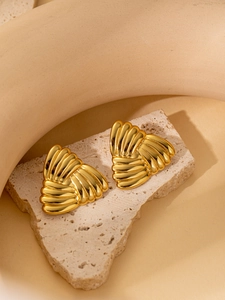 Close-up of gold shell earrings with striped texture on a beige stone stand