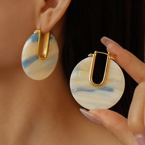 Detail of 18k gold-plated U-shaped hoop earrings with blue marble patterned charms