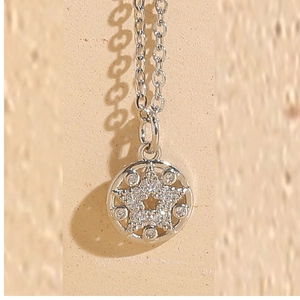 Macro shot of silver star pendant necklace with micro-paved zircons and polished finish