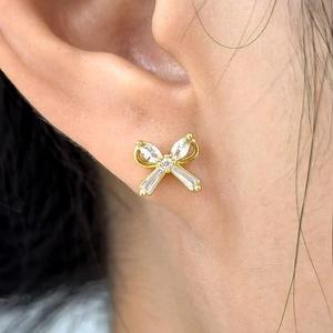 S925 sterling silver bow stud earrings with clear zircon stones on a female model ear