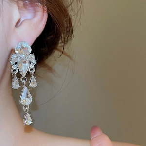 Macro di orecchini a nappa in argento con cristalli scintillanti indossati da una modella