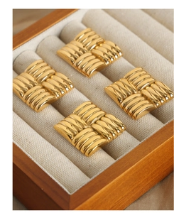 Close-up of square gold-plated titanium earrings featuring a detailed woven texture design