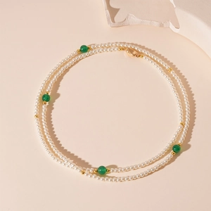 Détail d'un collier vintage multicouches avec perles blanches et perles en verre agate