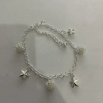 Detail view of silver metal anklet featuring polished stars and textured beads
