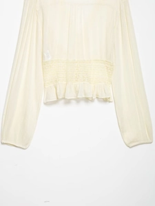 Detail of off-white chiffon blouse featuring intricate waist lace embroidery and ruffles