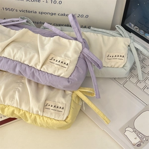Close-up of quilted cotton pencil cases in pastel purple, blue and yellow with side handles