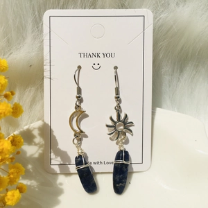 Detail of sun and moon asymmetrical earrings with blue raw stone and wire wrap style