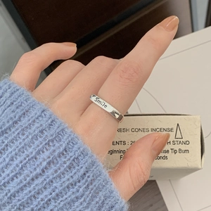 S925 sterling silver smile engraved open ring worn on finger against blue sweater