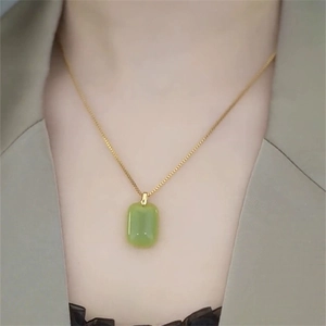 Elegant gold chain necklace with a green rectangular jade pendant shown on a model neck