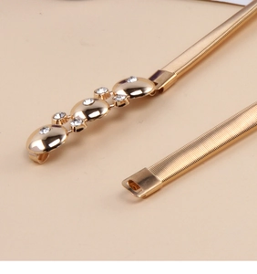 Detail of gold elastic metal belt buckle featuring sparkling rhinestones and round plates