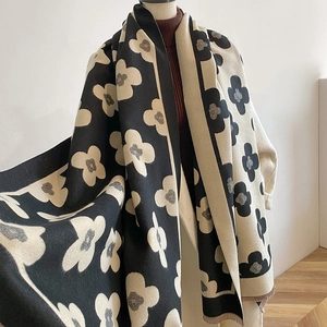 Close-up of thick winter scarf featuring a large black floral print and fringe details