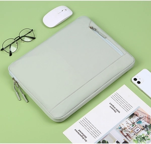 Light green laptop sleeve with dual zippers shown on a clean workspace desk
