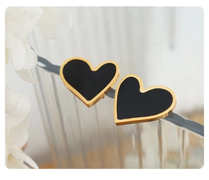 Macro shot of heart-shaped black acrylic earrings with gold steel borders
