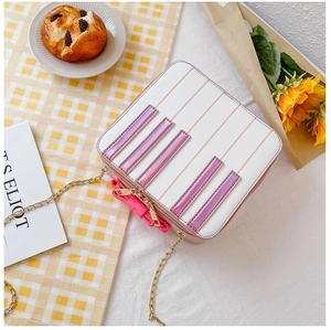Detail of white mini crossbody bag with pink bow, piano key stripes and gold chain