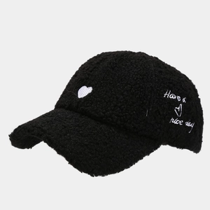Detail of black teddy fleece baseball cap featuring white heart embroidery detail