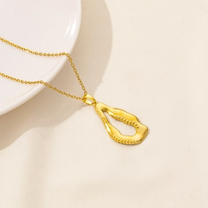 Detail of minimalist gold-plated necklace with abstract irregular hollow pendant on fabric