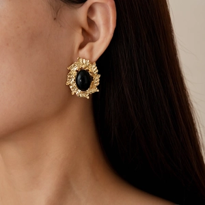 Close-up of vintage gold leaf frame earring with large black oval stone on model