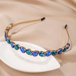 Elegant gold metal headband featuring blue and teal pear-cut crystals on satin background