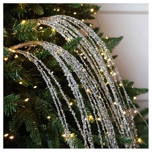 Silver glitter droplet tassel garland on a Christmas tree with warm glowing lights