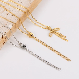 Detail of gold and silver bow pendant necklaces with lobster clasp on stone
