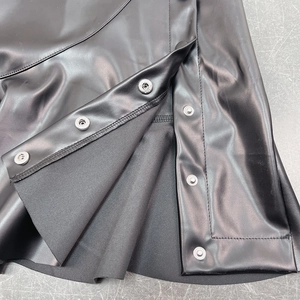 Detail view of black PU leather skirt featuring silver metal snap buttons and fine stitching