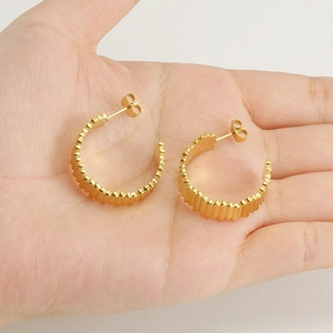 18K gold plated stainless steel ribbed hoop earrings held in hand for size reference