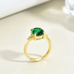 Vintage gold ring featuring a large oval emerald gemstone with zircon accents in four-claw setting