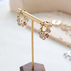 Golden hoop earrings with five colorful rainbow crystal pendants on a jewelry display stand