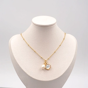 Elegant gold freshwater pearl necklace with shell pendant on a white mannequin