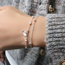 Detail of silver double-layered bracelet with ginkgo leaf charm and zircon on female wrist