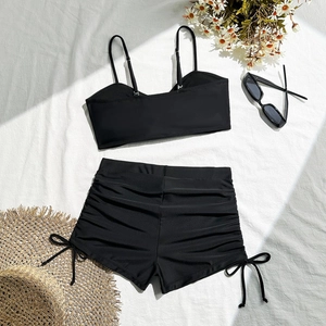 Two-piece black swimsuit with side drawstring boyshorts and thin straps on white fabric