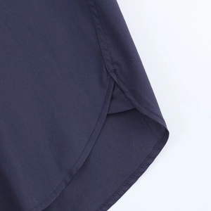 Detailed close-up of curved hem and stitching on dark blue poplin shirt fabric