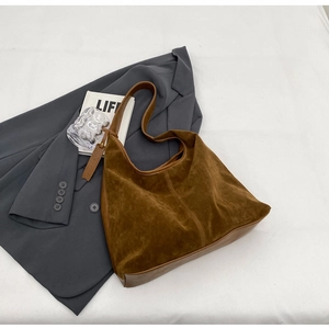 Detailed view of brown faux suede hobo shoulder bag styled with a grey blazer and decor