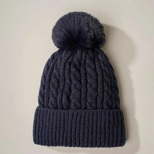 Navy blue cable-knit beanie with faux fur pompom for winter warmth and casual style