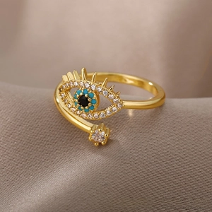 Macro shot of gold Evil Eye open ring with blue stones on champagne satin fabric