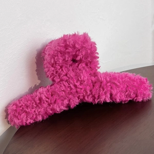 Macro detail of the fuzzy rose red plush fabric texture on a high-quality hair claw clip