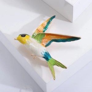 Detailed macro view of colorful enamel swallow brooch with yellow, white and green tones