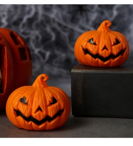 Detail of two orange Halloween jack-o'-lantern ornaments on dark spiderweb background