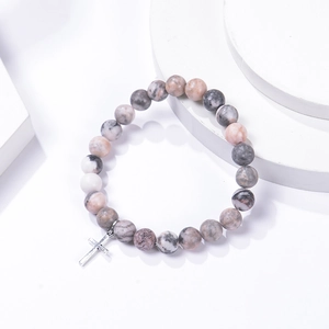Detailed close-up of pink zebra stone beads and silver cross charm on elastic bracelet