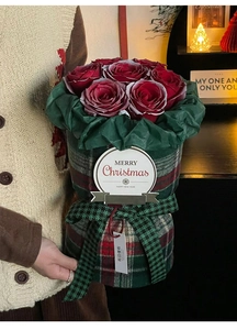 Close-up of red rose bouquet in British plaid fabric wrap with Merry Christmas gift tag