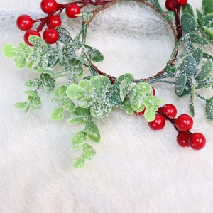 Macro shot of artificial red berries and snowy eucalyptus leaves on rustic brown vine