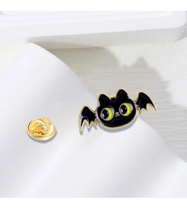 Detailed view of enamel cat bat brooch with gold alloy edges and green accents