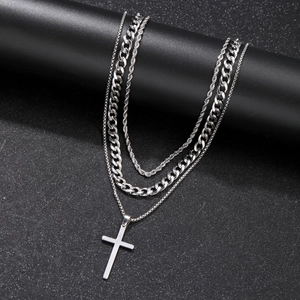 Macro view of three-layered stainless steel necklace featuring a cross pendant and twist chain