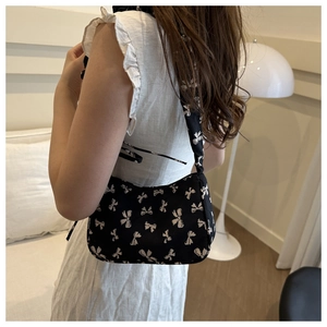 Detail of canvas shoulder bag featuring vintage bow pattern with drawstring pleated texture