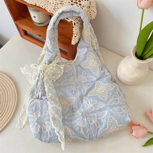Gros plan détaillé du sac en dentelle bleu clair avec broderie papillon et nœud blanc