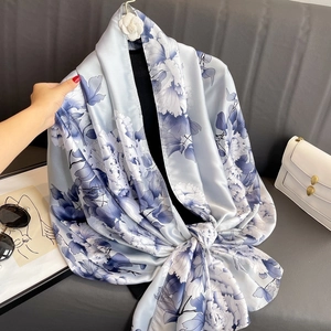 Elegant light blue silk satin scarf with dark blue floral print and draped finish